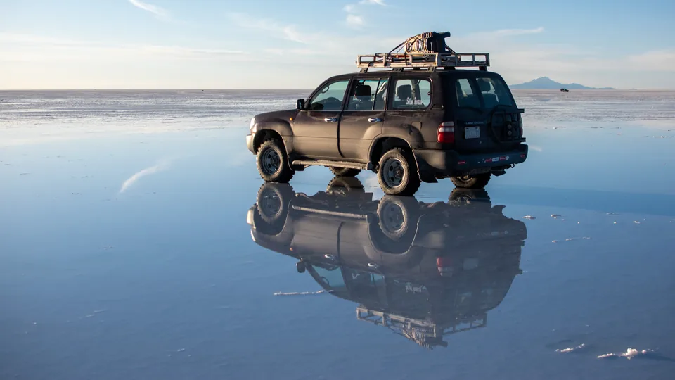 An off-road vehicle reflected in shallow water